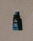 Ninth Wave After Sun Night Moisturiser bottle placed on the sand at the beach to highlight post-sun recovery