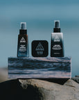 Ninth Wave Evening Routine products arranged on a rock at the beach.