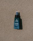 Ninth Wave Dawn Patrol Day Moisturiser bottle placed on the sand at the beach to reflect a surf-ready morning routine