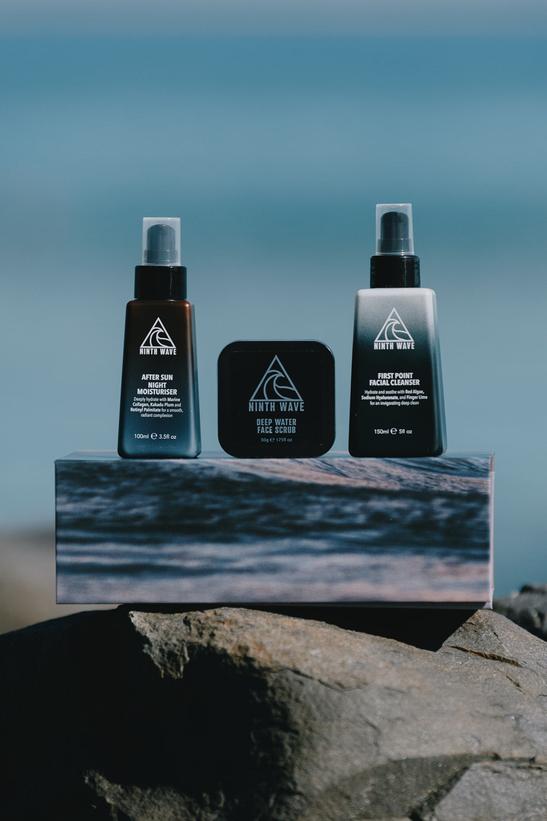 Ninth Wave Evening Routine products arranged on a rock at the beach.