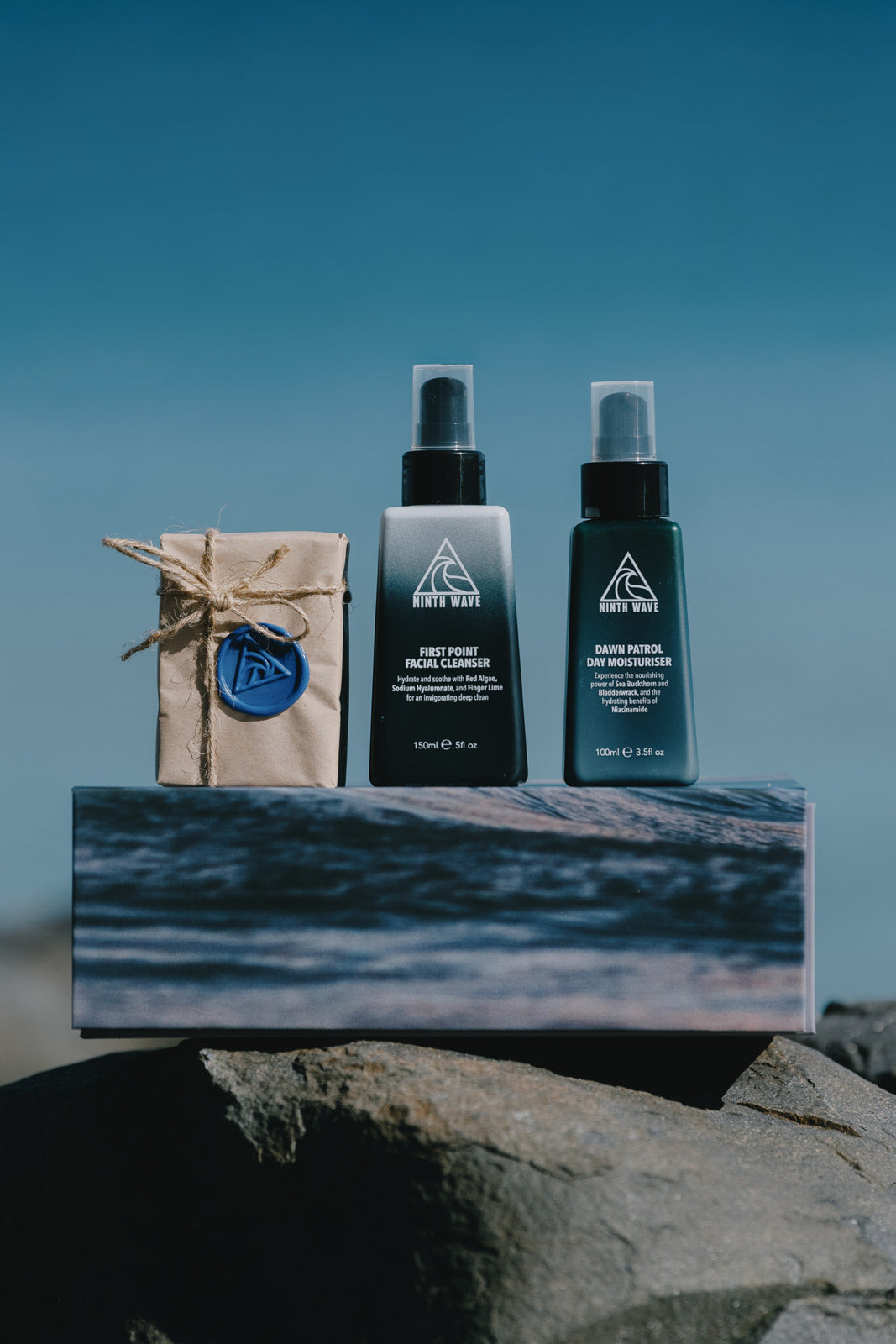Ninth Wave Body and Face Essentials kit displayed on its box at the beach